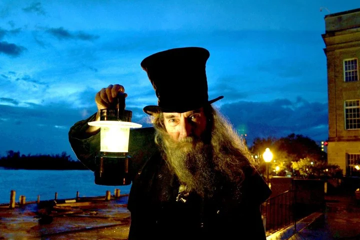 Costumed Ghost Walk of Old Wilmington guide holding a lantern beside the riverfront